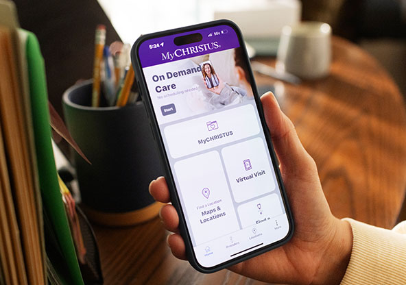 A hand holds the MyCHRISTUS app. The screen displays On Demand Care, MyCHRISTUS , Maps & Locations and Virtual visits.